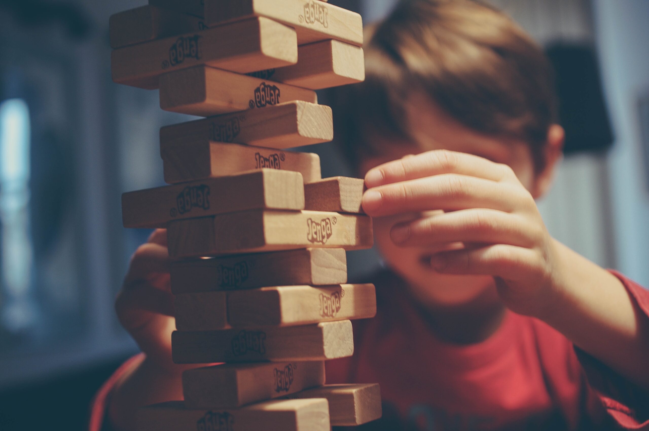 Young white boy playing wooden jenga game
